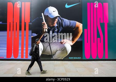 Londra, Regno Unito. 23 settembre 2025. La gente passa un'immagine del golfista Rory McIlroy sulla costruzione dell'allestimento esterno del Nike Store, in fase di riqualificazione, all'Oxford Circus. Rory McIlroy è uno dei membri chiave del Team Europe che gareggia contro gli Stati Uniti nella Ryder Cup a Bethpage Black a New York, dal 23 al 28 settembre e, guidato dal capitano Luke Donald, spera di ottenere la prima vittoria in trasferta alla Ryder Cup dal 2012 "miracolo a Medinah". Molti sostenitori europei sperano di farlo, giusto. Crediti: Stephen Chung / Alamy Live News Foto Stock