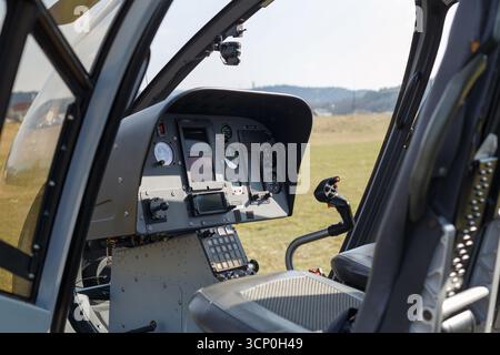 Vista dettagliata della cabina di pilotaggio di un elicottero che mostra gli strumenti e i comandi sotto la luce del sole e contro un paesaggio. Foto Stock