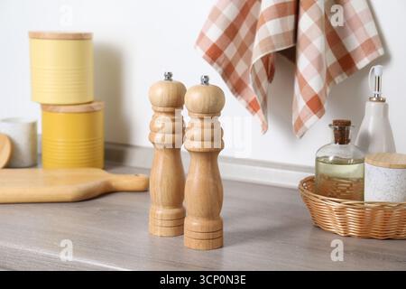 Sale, peperoni e bottiglie di olio su un bancone in legno grigio vicino alla parete bianca Foto Stock