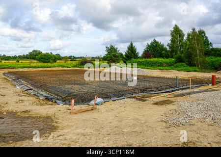 Fondamenta grandi preparate con rete di armature in acciaio e barriera al vapore in plastica, pronte per il versamento di solette in calcestruzzo in cantiere Foto Stock