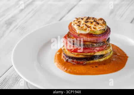 Verdure ratatouille al forno impilate in una torre vibrante, con strati dorati messi in risalto splendidamente Foto Stock