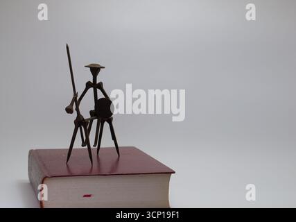 Una piccola immagine di Don Chisciotte fatta con le unghie su un libro. Foto Stock