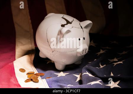 Un salvadanaio bianco mal riparato posto sulla bandiera americana circondato da penny sparsi. Foto Stock