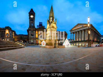 Una vista al crepuscolo di Chamberlain Square a Birmingham con un monumento storico, la galleria d'arte di Birmingham, una torre dell'orologio e alberi di Natale festivi. Il Foto Stock