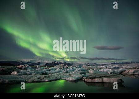 Aurora boreale sulla laguna del ghiacciaio Jökulsárlón, iceberg e riflessi, Parco Nazionale di Vatnajökull, Islanda meridionale. Foto Stock