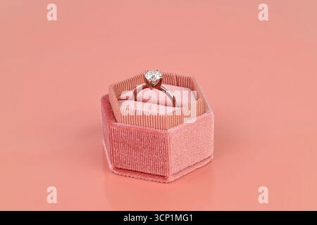 Un anello è in una scatola di velluto rosa. L'anello è bianco e lucido Foto Stock