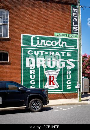 Lincolnton, North Carolina, Stati Uniti d'America - 14 luglio 2025: Cartellone storico che pubblicizza i farmaci Lincoln Cut-rate, con una "Ladies Room", sulla parete laterale del mattone Foto Stock