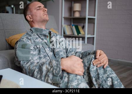 Soldato seduto sul pavimento soffre di disturbo da stress post-traumatico Foto Stock