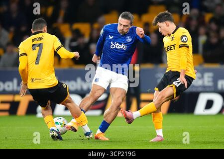 Jack Grealish (centro) dell'Everton combatte per il pallone con Andre (sinistra) dei Wolverhampton Wanderers e Rodrigo Gomes durante la partita del terzo turno della Carabao Cup al Molineux Stadium di Wolverhampton. Data foto: Martedì 23 settembre 2025. Foto Stock