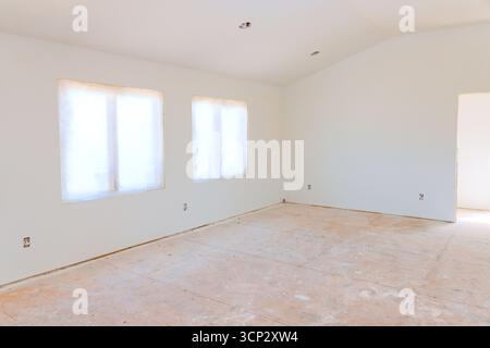 Sala luminosa e vuota, dotata di tre grandi finestre, che forniscono luce naturale e attendono un design interno rinnovato. Foto Stock