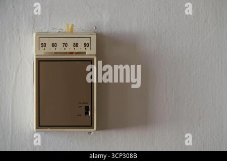 Un vecchio termostato analogico di controllo della temperatura per un forno è mostrato su una parete da vicino, con testo o spazio di copia a destra. Foto Stock
