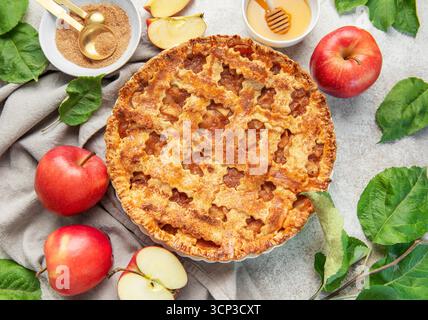 Classica torta di mele circondata da mele fresche, miele, zucchero di canna e decorata con foglie di mele Foto Stock