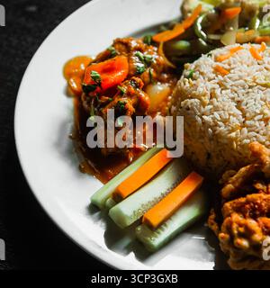 Pollo fritto croccante con curry cremoso di anacardi, riso fritto e verdure saltate Foto Stock