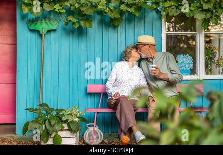 Coppie anziane che si baciano in giardino in una giornata di sole Foto Stock