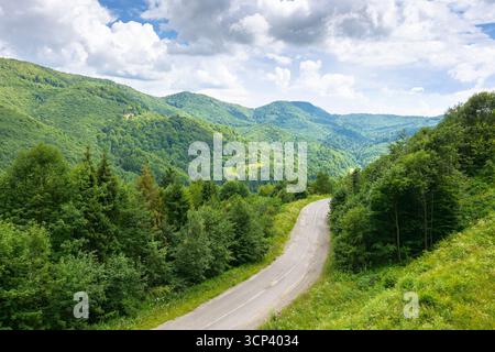 strada che attraversa il paesaggio montano in estate. vista panoramica dall'alto. verde paesaggio naturale in luce dappata sotto il cielo nuvoloso. splendida valle con pass Foto Stock