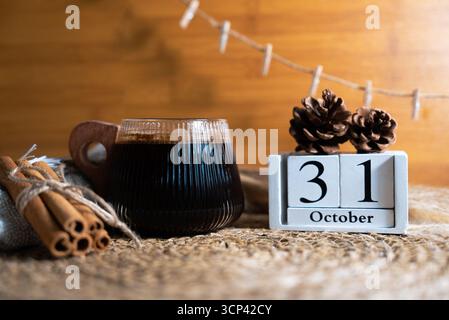 La calda natura morta autunnale con caffè caldo, oggetti di scena rustici, zucche e blocchi di calendario in legno è fissata al 31 ottobre. Foto di scorta perfetta per la stagione. Foto Stock