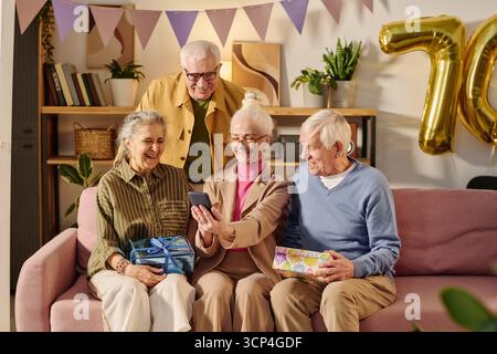 Amici anziani che festeggiano il compleanno e portano Selfie insieme Foto Stock