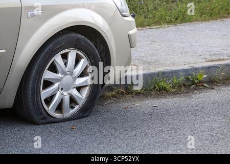 Pneumatico anteriore sgonfio sulla vettura parcheggiata Foto Stock