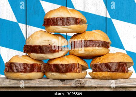 Baviera, Germania - 17 settembre 2025: FOTOMONTAGGIO, Leberkässemmel bavarese impilato su una torre di fronte alla bandiera bavarese *** FOTOMONTAGE, Bayerische Leberkässemmel gestapelt zu einem Turm vor der bayerischen Flagge bzw. Fahne Foto Stock