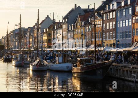 Barche e colorate case danesi tradizionali alla luce del sole serale a Nyhavn, Copenaghen, Zelanda, Danimarca, Europa Foto Stock