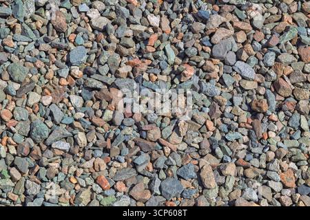 Una vista di una varietà di rocce fluviali e ciottoli di varie dimensioni, forme e colori sparsi sul terreno, creando uno sfondo testurizzato. Foto Stock