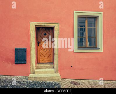 Primo piano di una porta in legno antico splendidamente intagliato, posta in un portale in pietra con dettagli architettonici classici. Foto Stock