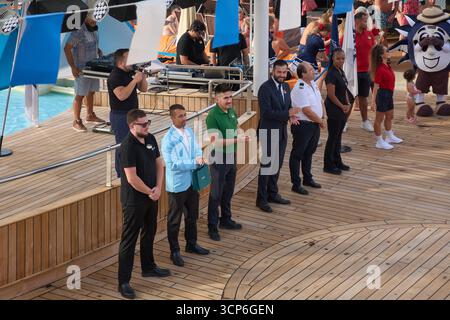 Venezia. Italia - 24 settembre 2025: Gli ufficiali delle navi da crociera e l'equipaggio vengono introdotti sul ponte della piscina durante una festa vivace con un DJ e i passeggeri si divertono Foto Stock