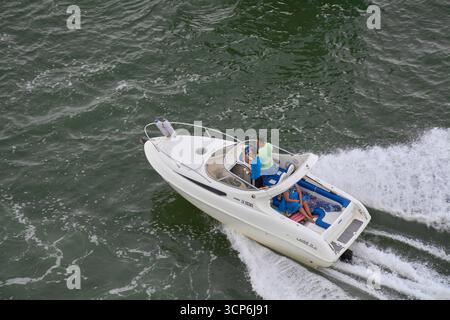 Venezia. Italia - 24 settembre 2025: Un uomo pilota il motoscafo mentre gli amici o la famiglia si rilassano in cabina durante una giornata di sole di boa ricreativo Foto Stock