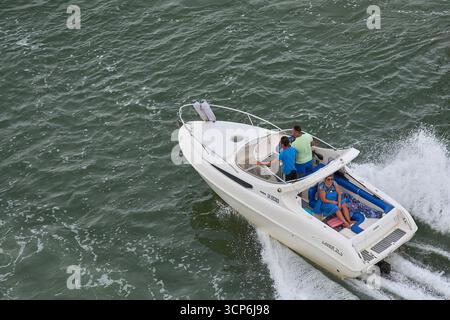 Venezia. Italia - 24 settembre 2025: Una veduta aerea mostra un gruppo di quattro persone che navigano su un cabinato bianco Laver 21,5, muovendosi a velocità sostenuta Foto Stock