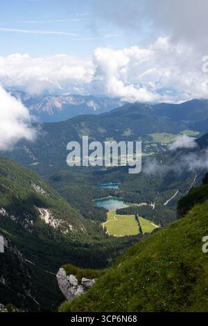 Vista panoramica dal monte Mangart verso la valle dei Laghi delle Fusine nelle Alpi Giulie, in Italia, con cime e prati alpini spettacolari Foto Stock