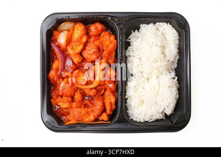 Pollo dolce e acido con riso. Pasto da asporto asiatico in scatola. Cubetti di pollame smaltati rossi. Riso bianco appiccicoso al vapore. Porzione di cucina orientale esotica. Foto Stock
