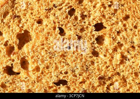 Primo piano della consistenza del pane fresco. Superficie al forno dorata con struttura porosa e fori. Dettagli macro dello sfondo crosta e briciola. Forno biologico naturale Foto Stock
