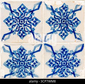 Un primo piano di quattro piastrelle azulejo portoghesi bianche e blu, che mostrano il loro intricato motivo tradizionale simile a un fiocco di neve e sottili segni di età e usura. Foto Stock