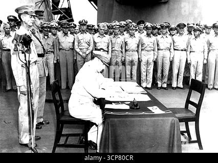 Il generale Douglas MacArthur, comandante supremo alleato, firma il documento di resa giapponese il generale dell'esercito statunitense Douglas MacArthur, comandante supremo alleato, firma il documento di resa giapponese 1 settembre 1945 a bordo degli U.S.S. Missouri. Dietro al generale McArthur ci sono il tenente generale statunitense Jonathan Wainiright (a sinistra), eroe di Rataan e Corridor che fu trovato in un campo di prigionia giapponese il 20 agosto 1945, il tenente generale britannico Arthur E. Percival, che fu costretto a consegnare Singapore ai giapponesi. Entrambi furono liberati dalla carpa della prigione giapponese a Sian, in Manciuria, dai paracadutisti statunitensi Foto Stock