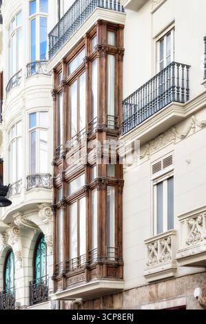 Un primo piano di una facciata ornata di un edificio storico a Valencia, in Spagna, con una tradizionale finestra a bovindo in legno e un intricato balcone Foto Stock