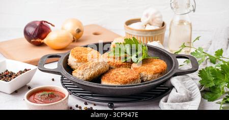 Padella con gustose cotolette di carne sul tavolo Foto Stock
