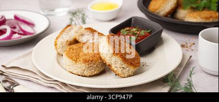 Piatto con gustose cotolette di carne e salsa sul tavolo, primo piano Foto Stock