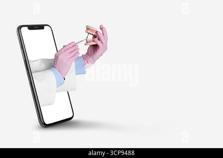 Collage con lo smartphone e le mani del dentista tenendo il modello a mascella e lo specchio sullo sfondo chiaro Foto Stock