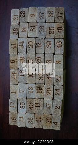 Primo piano di blocchi di legno con numeri incisi disposti in una griglia su una superficie scura. Foto Stock