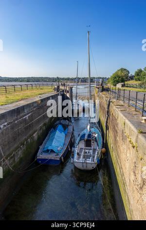 Yacht e piccole imbarcazioni ormeggiati in una camera di blocco a Spike Island, Widnes, durante la bassa marea Foto Stock