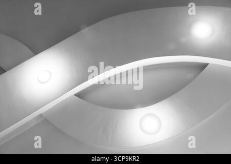 Una scena architettonica astratta in scala di grigi con superfici curve e luci incassate che diffondono una luce soffusa. Le linee pulite e moderne trasmettono calma e raffinatezza Foto Stock