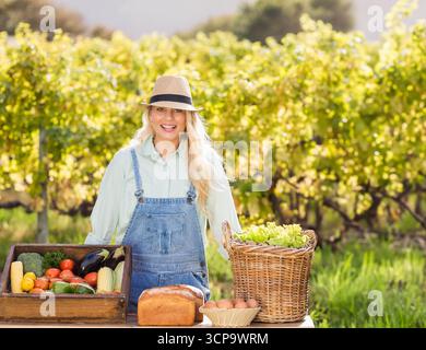 Tavolo in legno con verdure raccolte, pane, uova e lattuga in filari di vite presso lo stand dell'azienda agricola Foto Stock