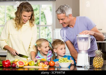 Famiglia di quattro pezzi di frutta sul tagliere e frullatore in funzione sul ripiano della cucina Foto Stock