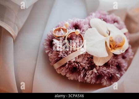 Le fedi nuziali sono elegantemente esposte su una composizione floreale in un ambiente romantico Foto Stock