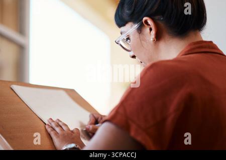 Artista, disegno e apprendimento su carta nel processo di creatività in studio al college con progetto. Arte, studentessa e donna che progettano uno schizzo con una matita Foto Stock