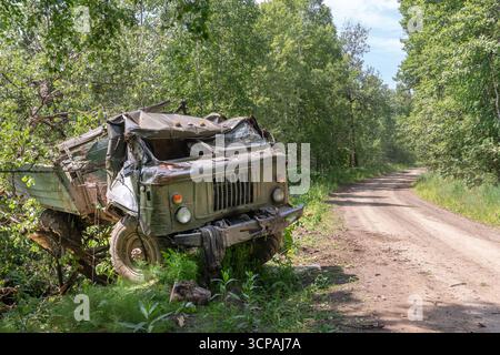 Logistica militare. Un camion militare russo o ucraino Gaz 66 di fabbricazione sovietica, fatto esplodere o fatto esplodere, si trova rovesciato vicino a una strada in Ucraina. Esplosione Foto Stock