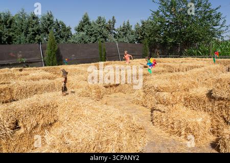 I bambini navigano attraverso un divertente labirinto di balle di fieno in una giornata di sole Foto Stock