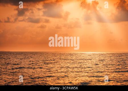 Il fantastico tramonto dorato sul mare calmo con cielo spettacolare, nuvole morbide e raggi luminosi del sole sognano un tranquillo sfondo naturale e una tranquilla vista sul mare Foto Stock