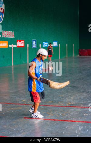 Un pelotari filippino con il cesta che gioca a jai alai, un tempo sport basco molto popolare nelle Filippine, in un fronton locale a Manila Foto Stock