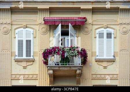 Balcone affascinante con fiori in fiore sulla facciata ornata di un edificio vintage Foto Stock